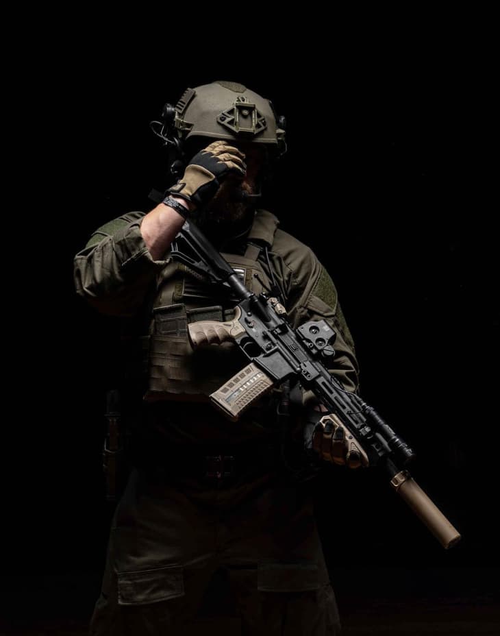 Man in combat clothing holding rifle with FAB Defense Accessories equipped.